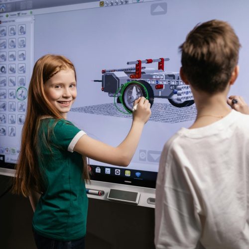two kids standing by an interactive board